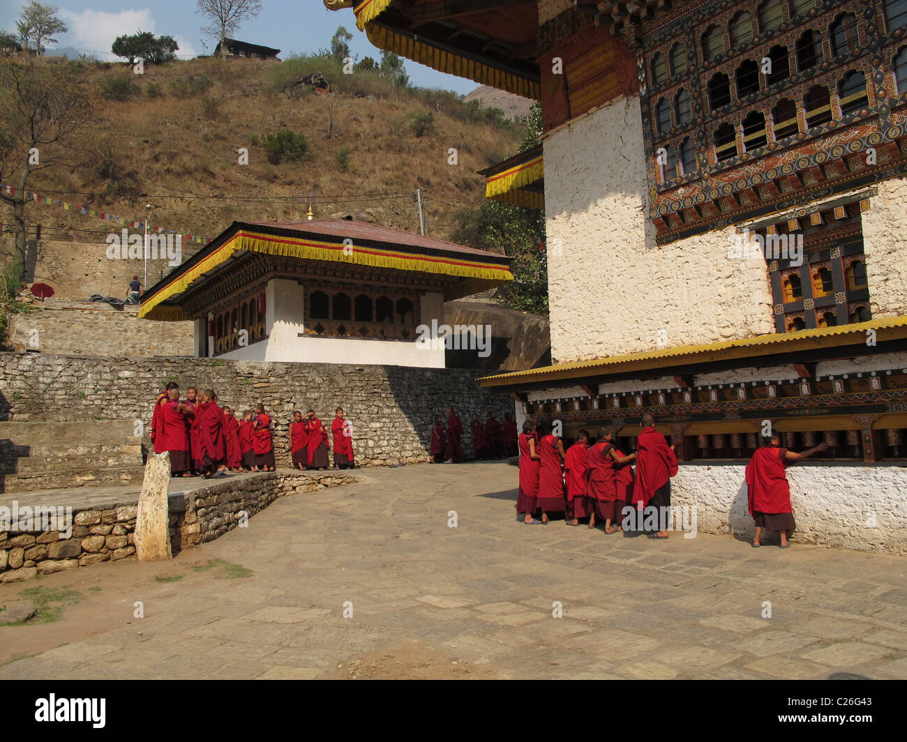 Monks at the prayer wheels, Gom Kora temple, a sacred meditation site of Guru Rimpoche, north of Trashigang, East Bhutan Stock Photo