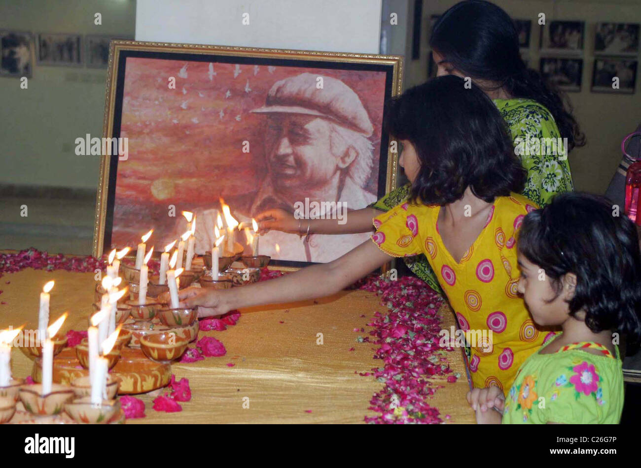 Children lighten candles in front of portrait of Zulfiqar Ali Bhutto Founder of Peoples Party (PPP) during a ceremony Stock Photo