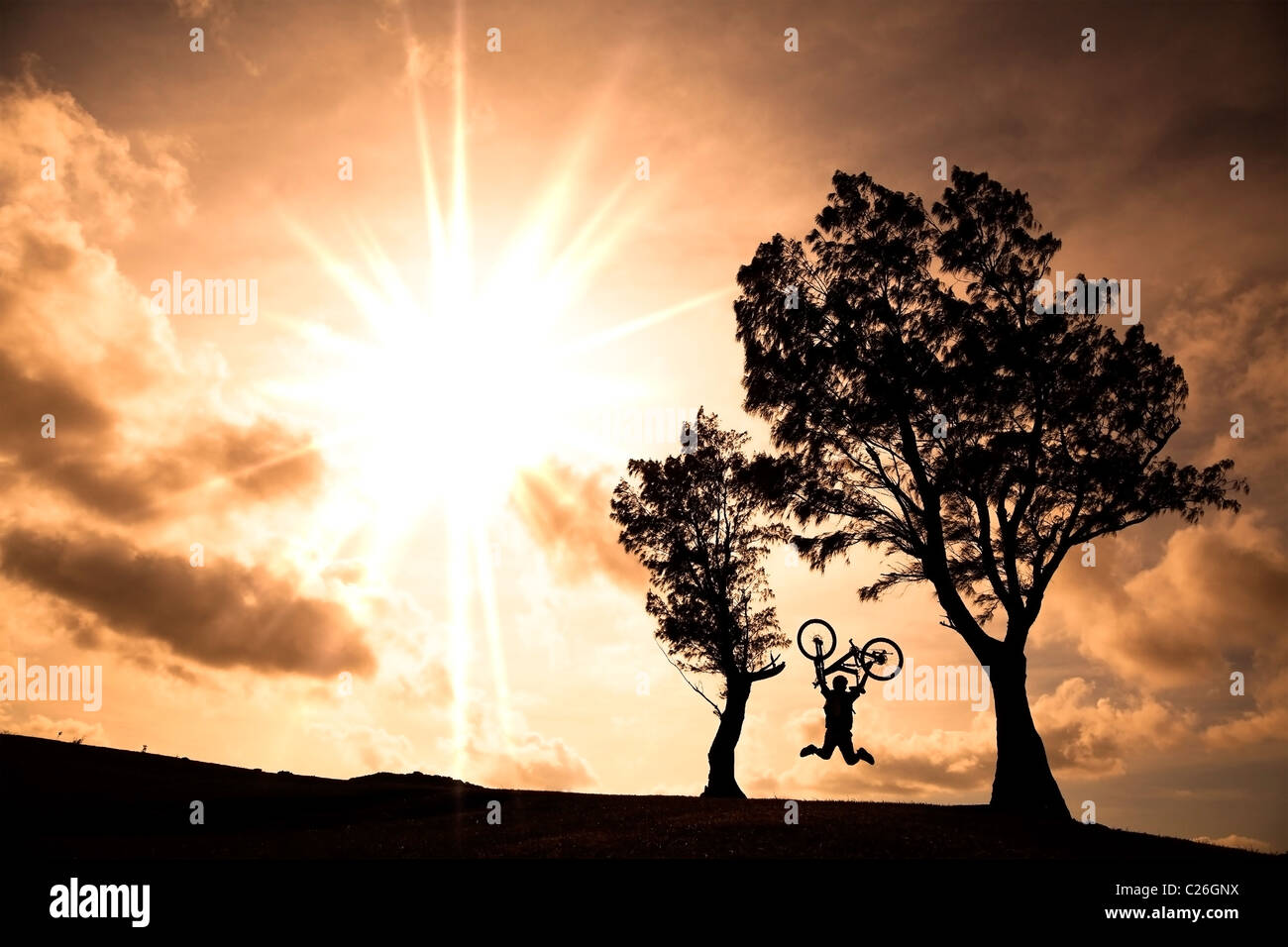 Happy rider holding bicycle and jumping on the hill Stock Photo