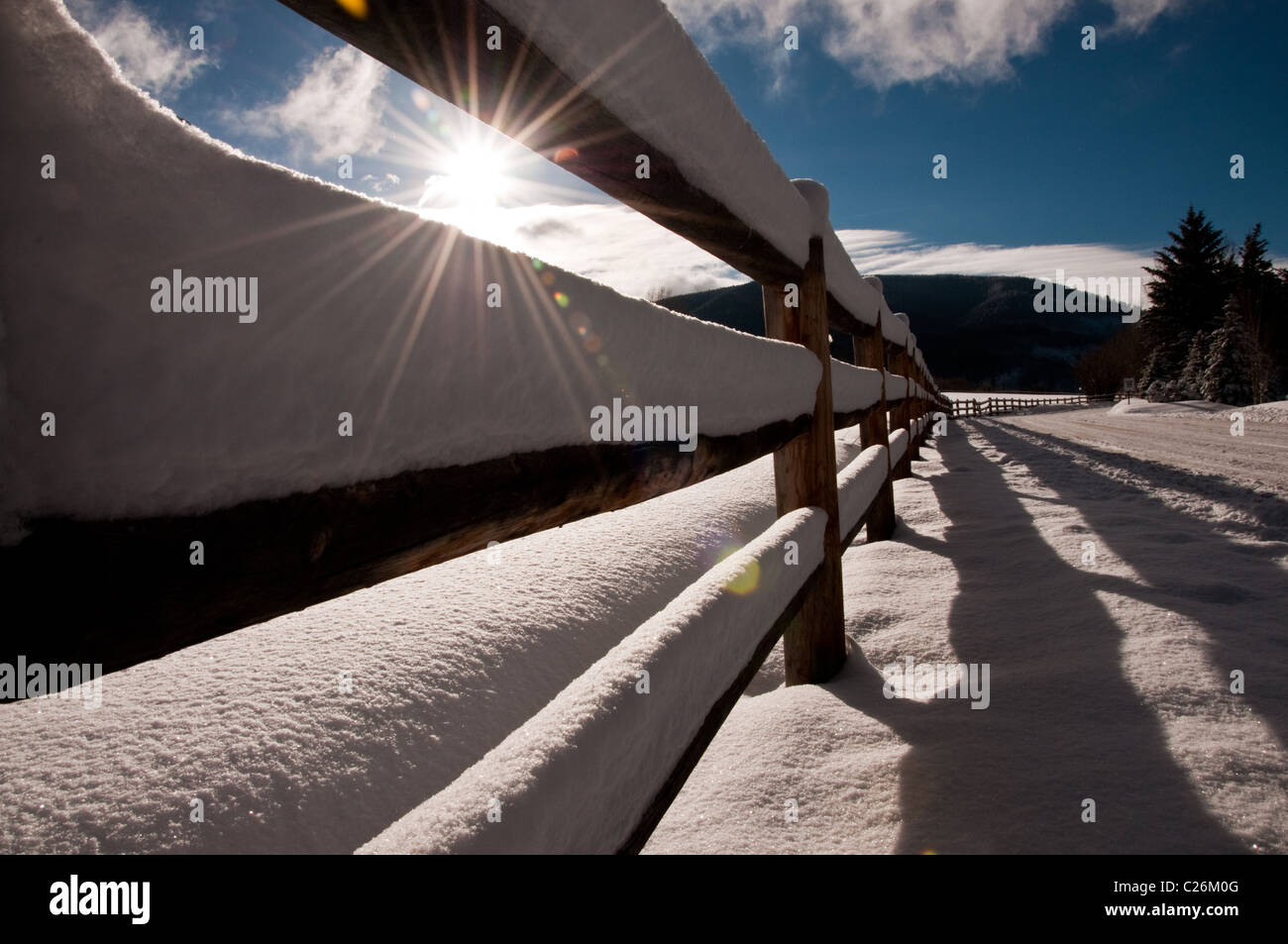 The sun shinning through a snow covered wooden fence Stock Photo - Alamy