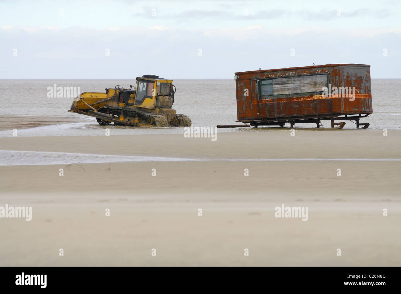 Сaterpillar tractor cross the river flows into the Gulf of Ob and pulls the shack on the skids. Yamal peninsula, Russia Stock Photo