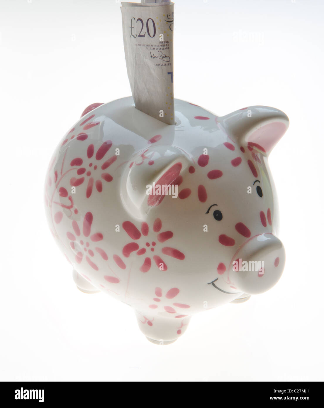 Piggy Bank with a £20 Pound note being inserted Stock Photo