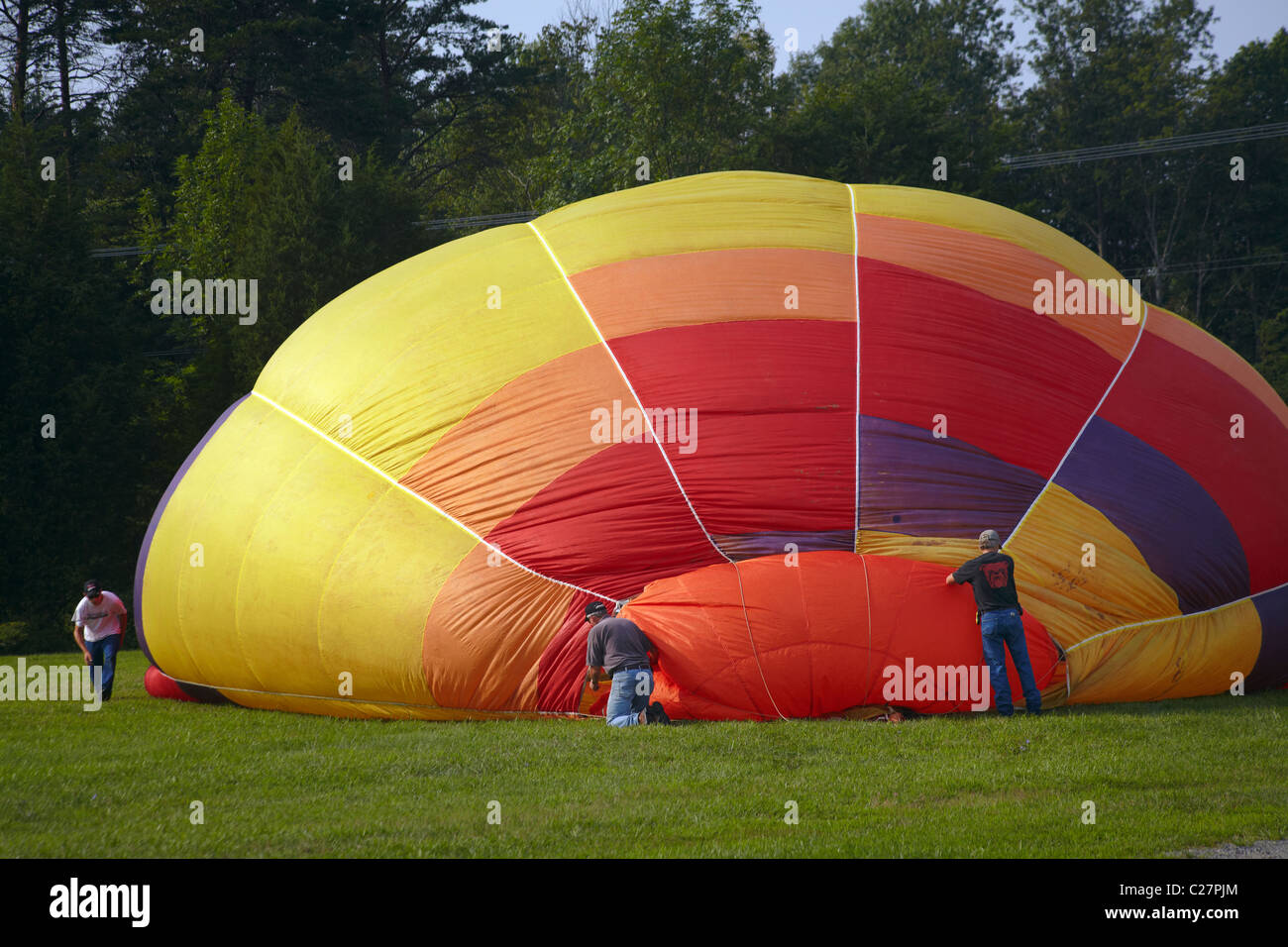 Three men work the rigging of an inflating hot air balloon. Stock Photo