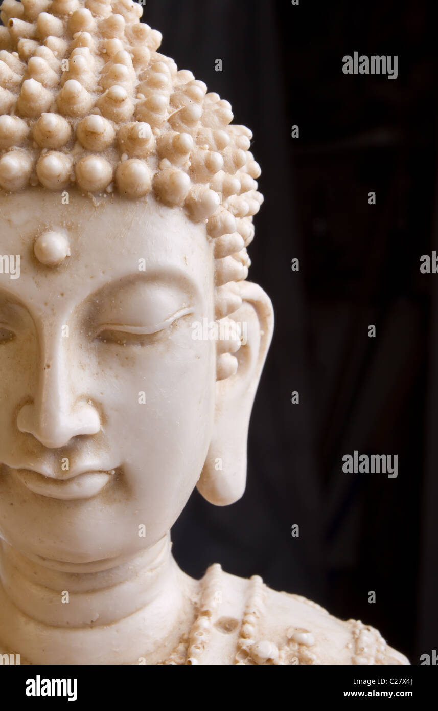 Close up of Buddah statue face against dark background. Stock Photo