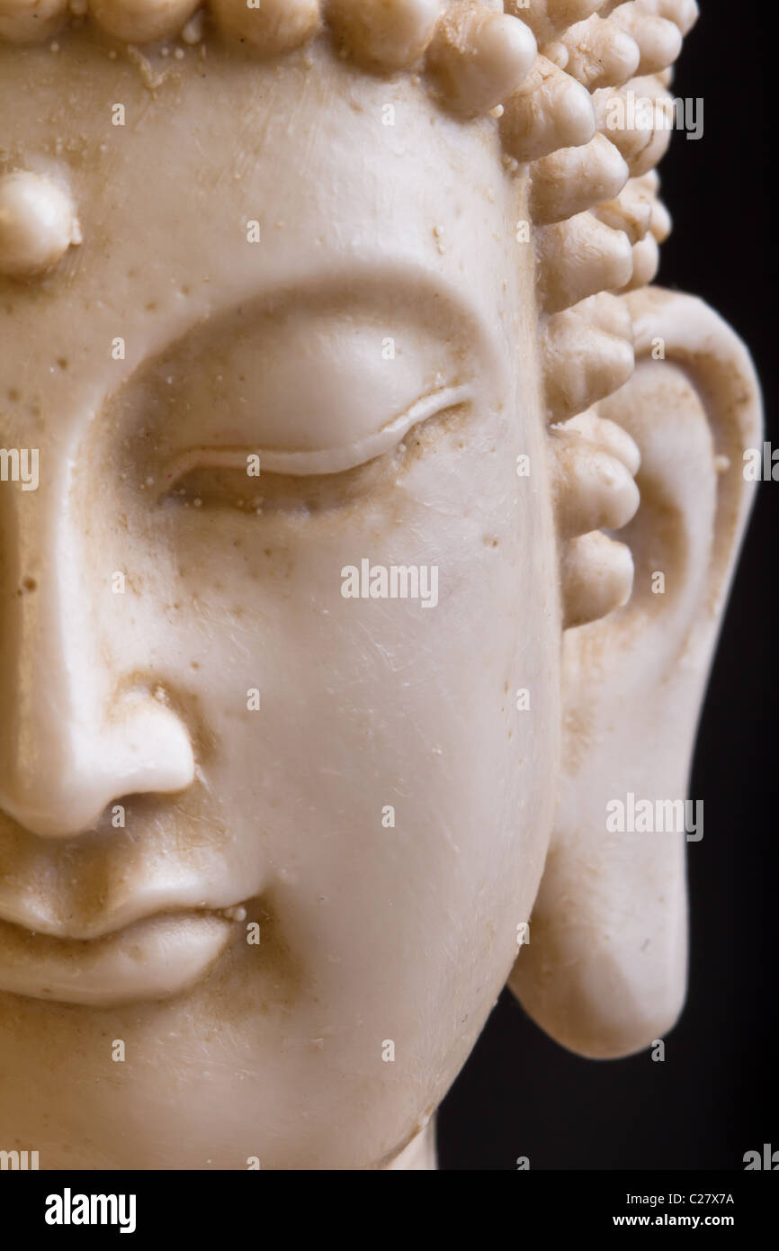 Close up of Buddah statue face against dark background. Stock Photo