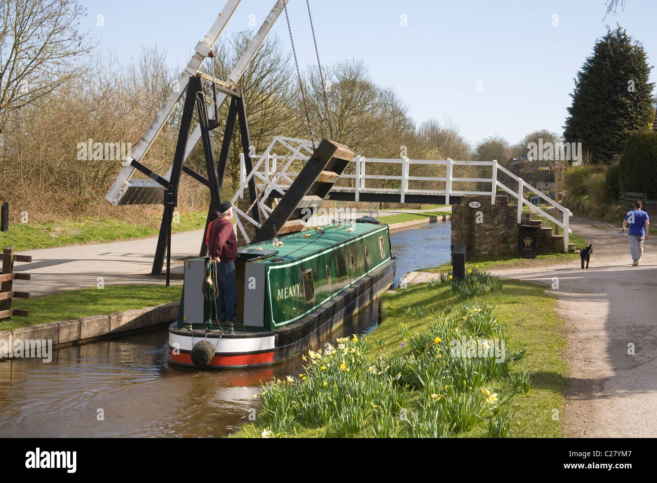 Froncysyllte North Wales White bearded helmsman steering narrowboat through open swing road bridge on Shropshire Union Canal Stock Photo