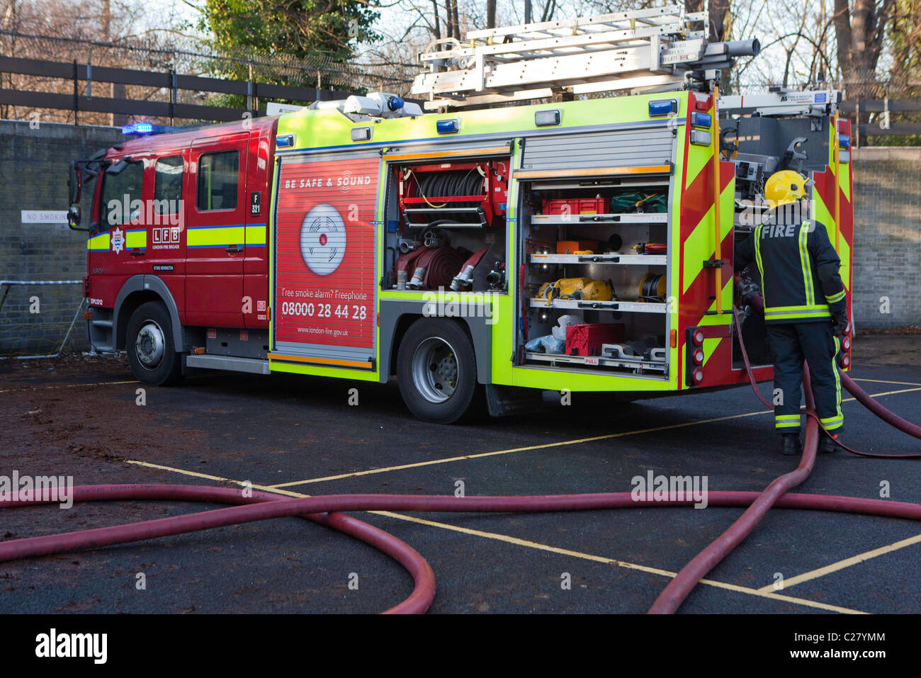 London Fire Brigade, station training session. A Fire fighter connects the hoses to the fire engine. Stock Photo