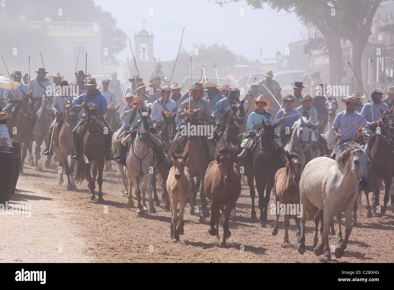 Riders herding horses from the Doñana National Park through El Rocio during the round up of the marsh mares (Saca de as Yeguas) Stock Photo