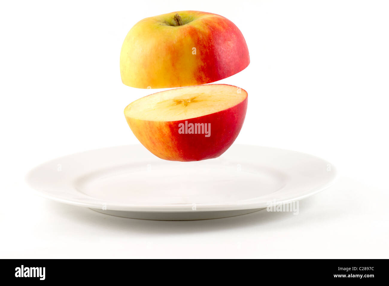 Sliced Apple hovering over white plate Stock Photo