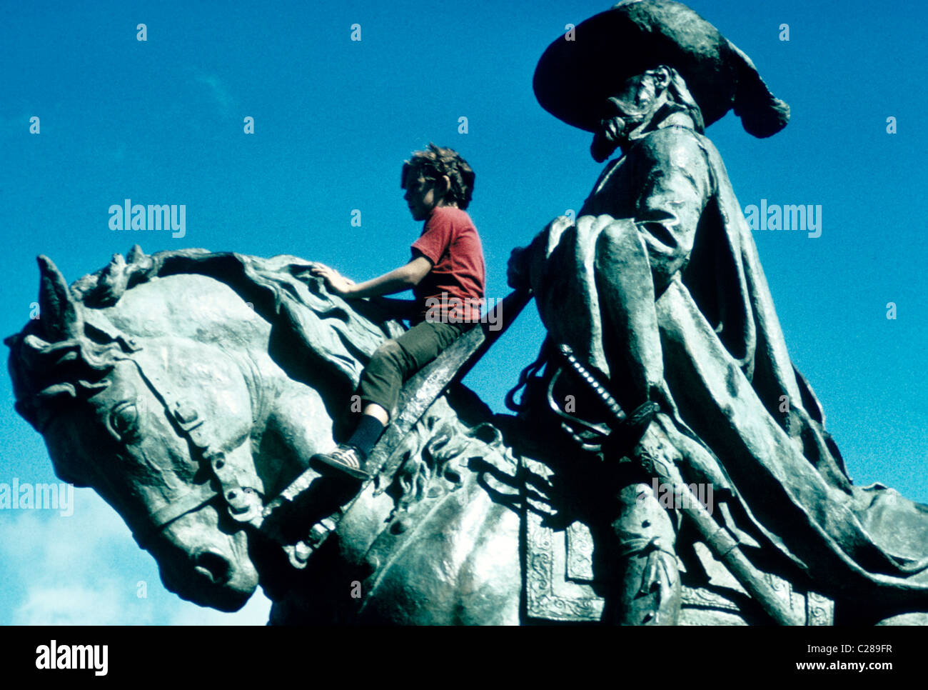 Young boy plays on statue of Conquistador riding on horse in a San Francisco Park Stock Photo