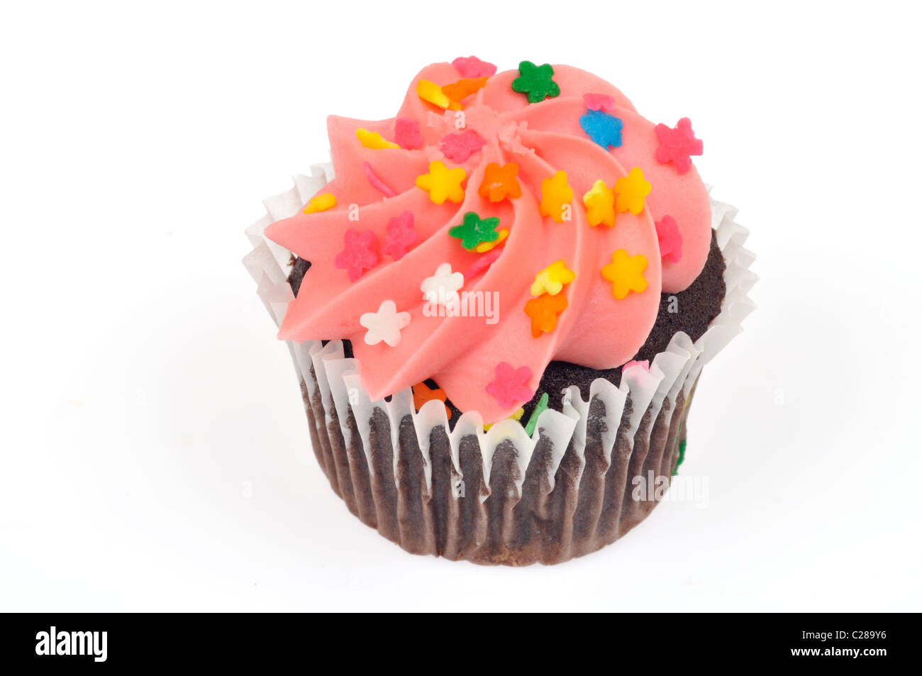 Chocolate cupcake decorated with pink icing and colorful sprinkles on white background, cutout. Stock Photo
