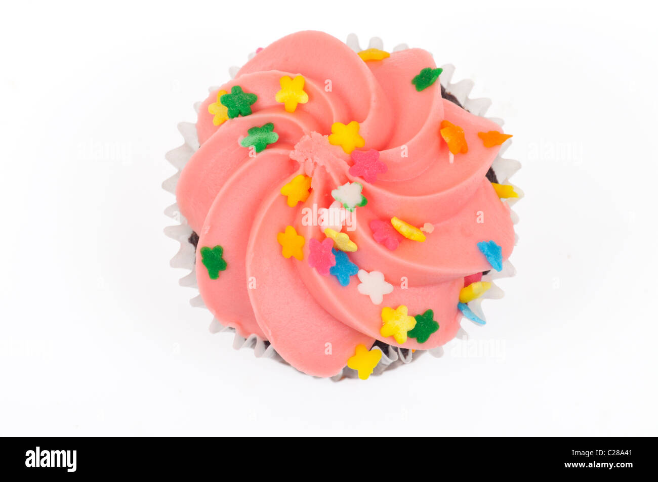 Chocolate cupcake with pink icing decorated with sprinkles from above on white background cut out. Stock Photo