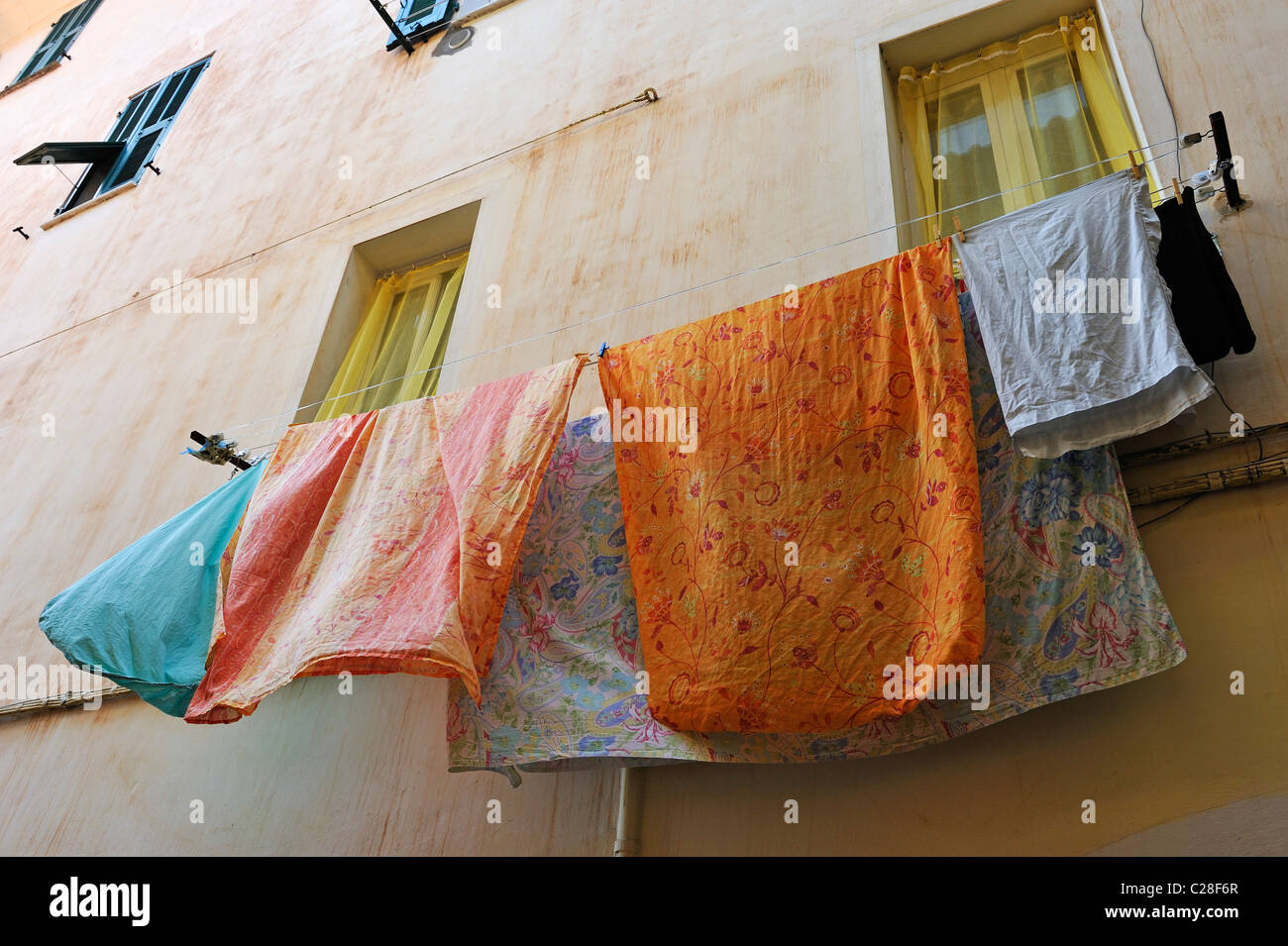 Laundry hanging on clothesline outside the windows of houses in Ventimiglia, Italy Stock Photo
