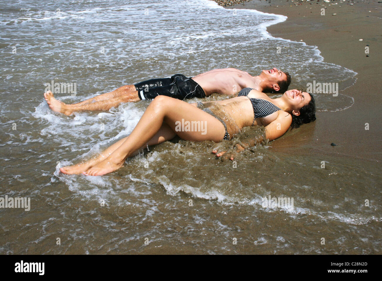 Couple enjoying cold sea water on beach. Stock Photo