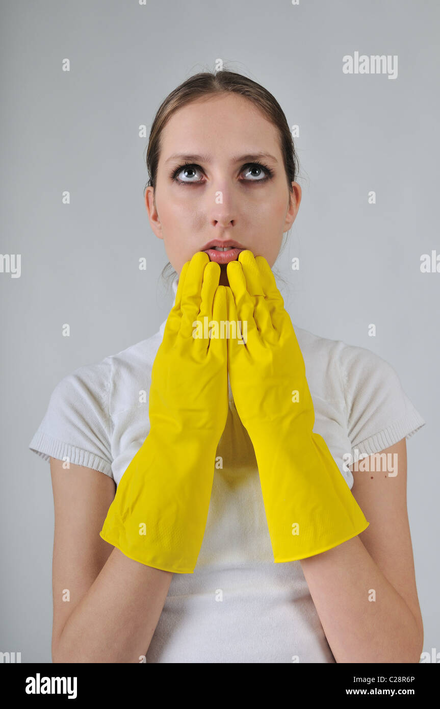 Young woman wearing yellow work gloves with thoughtful expression Stock