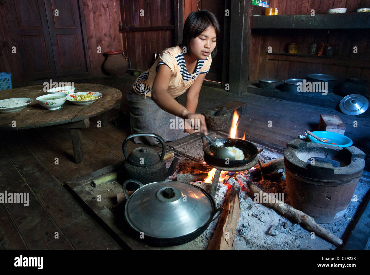 young woman cooking on open fire in wooden house. Mindayik. shan Hills. Myanmar Stock Photo