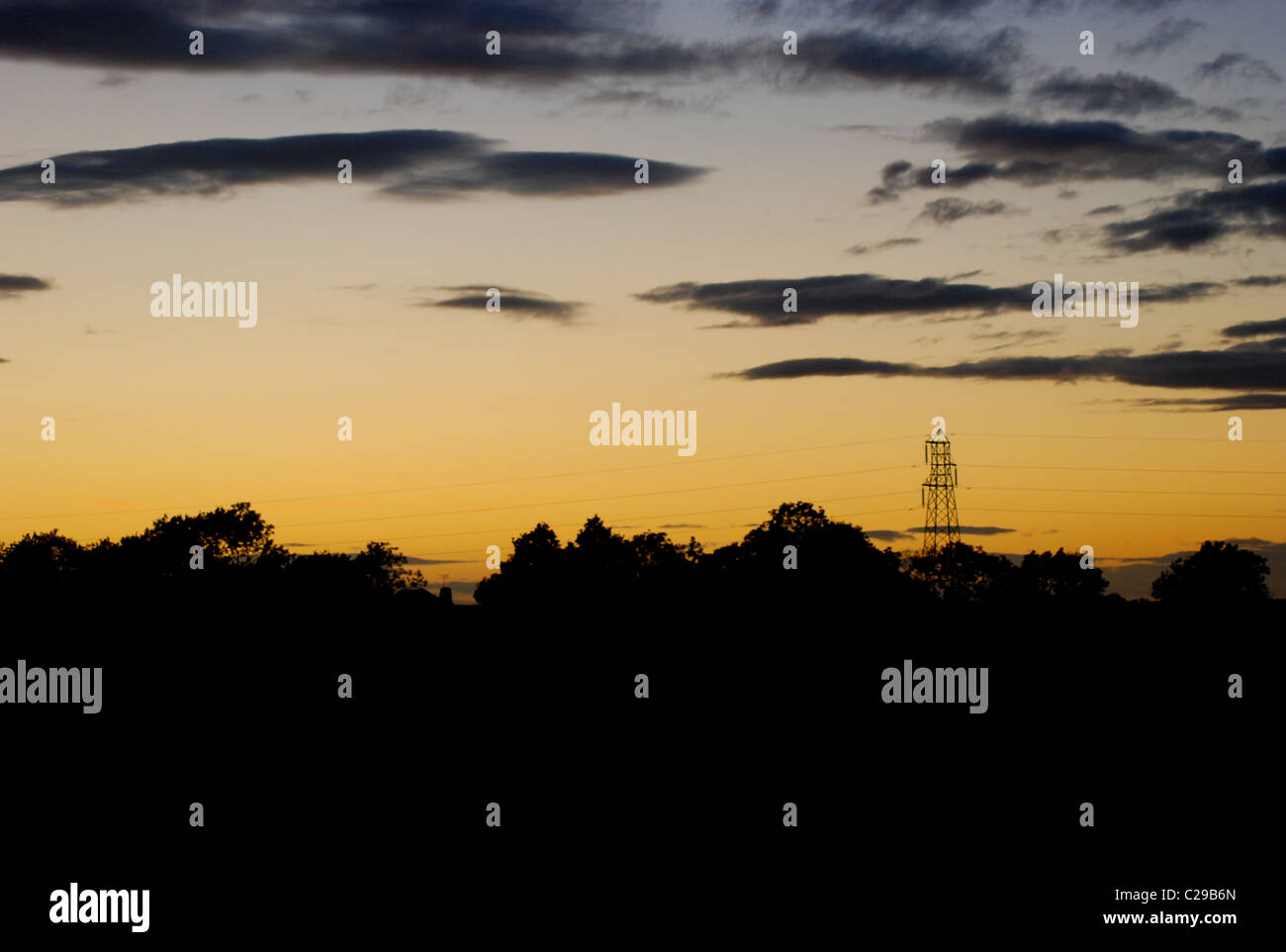 A photo showing the sun setting over some power lines and trees Stock ...