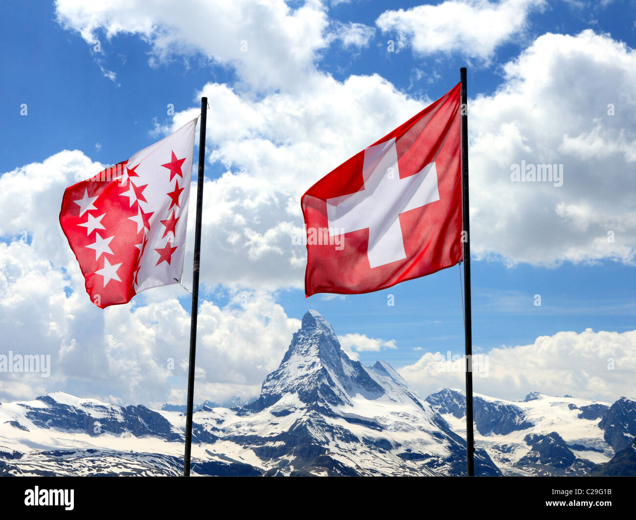 swiss flag and flag of canton Valais fly in front of mountain Matterhorn range Stock Photo