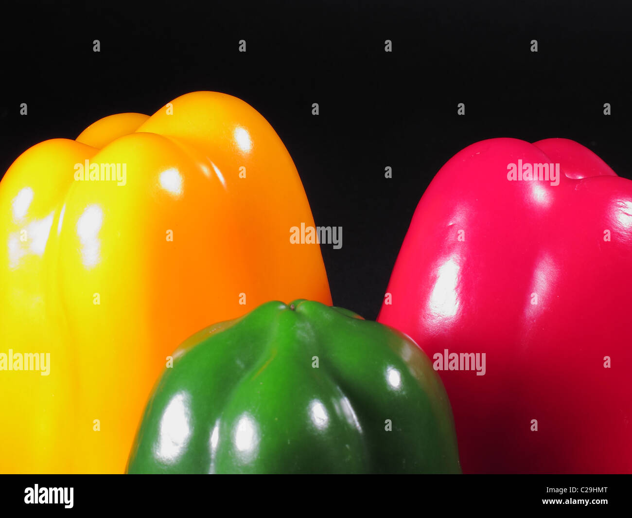 Three peppers of different colors on a black background Stock Photo