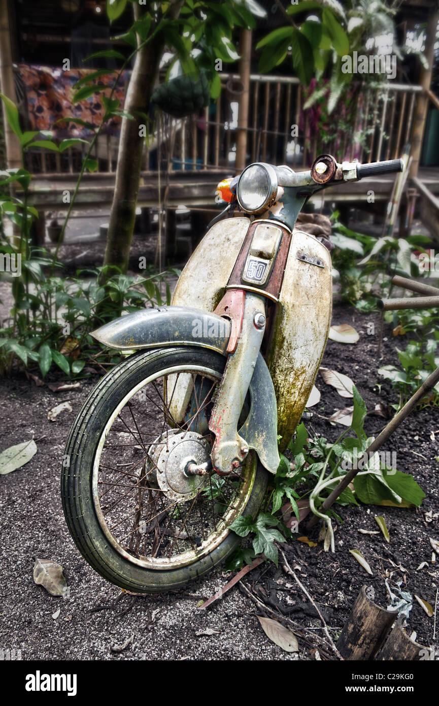 A dilapidated, classic Honda 50cc Stepthru moped outside a jungle dwelling Stock Photo