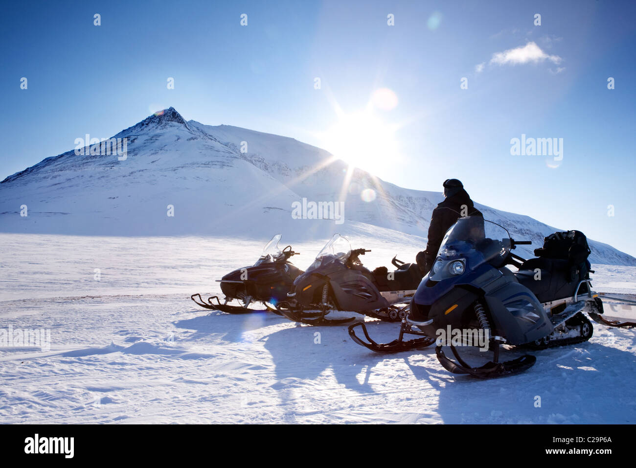 Three snowmobiles and a winter landscape with mountain Stock Photo