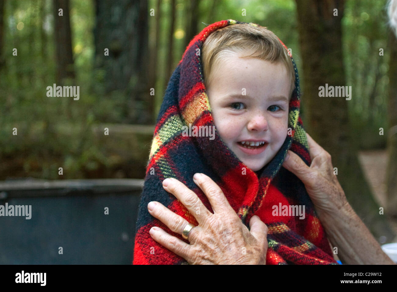 a 2 year old boy gets a blanket wrapped around him to protect him from the cold. Stock Photo