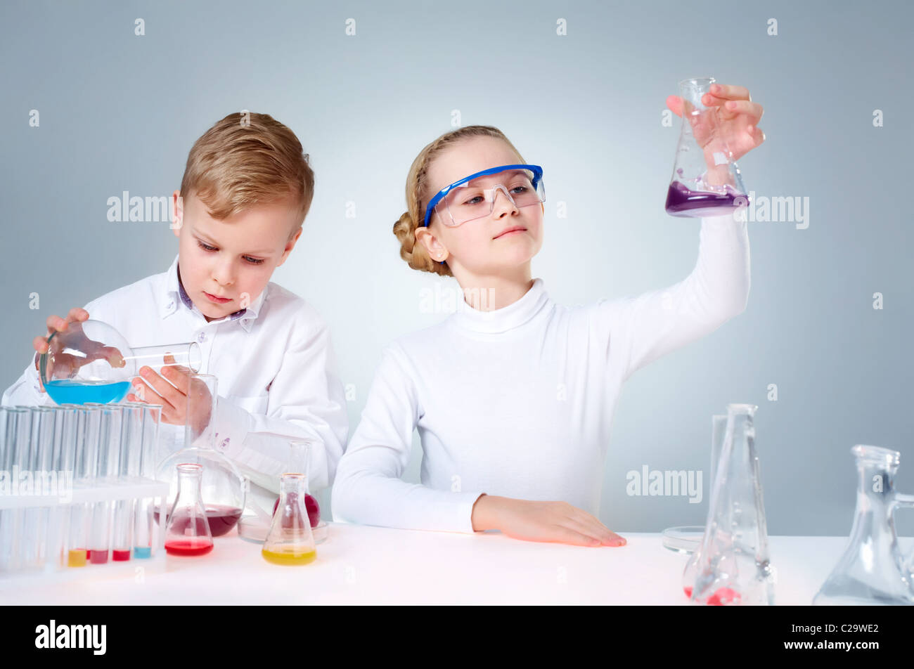 A little boy pouring liquid into a tube and his assistant shaking a ...