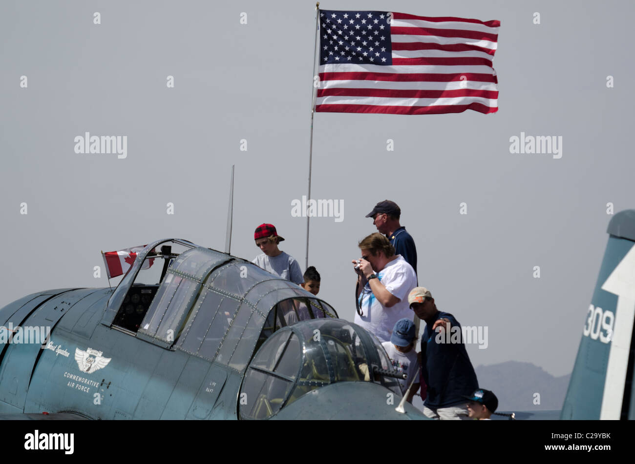 Spectators climb up on a Grumman Avenger at the Luke Days air show at