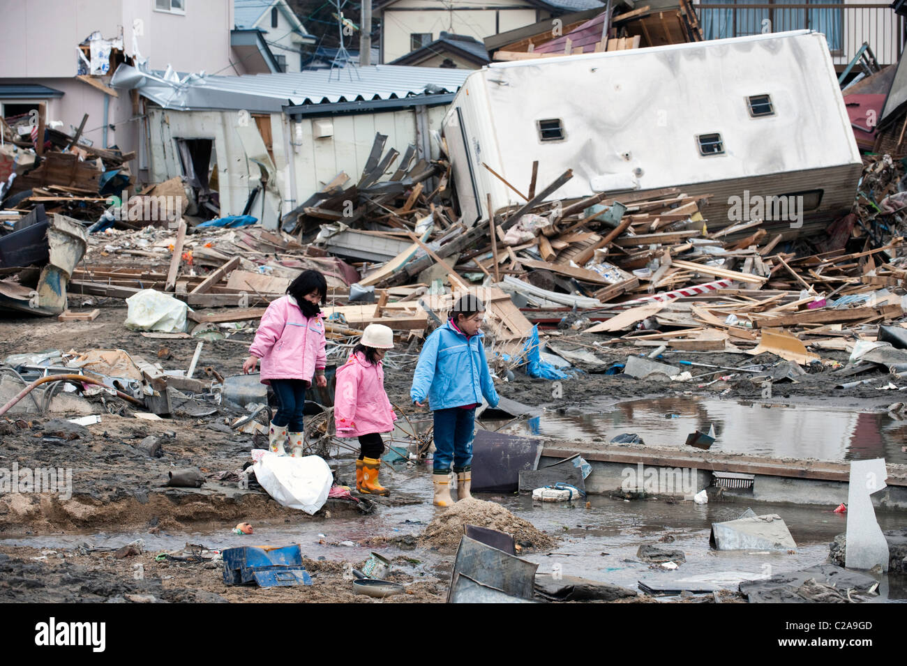 Japanese children look at the fishing boats, cars and houses were completely destroyed after a 9.0 Mw earthquake Tsunami Stock Photo
