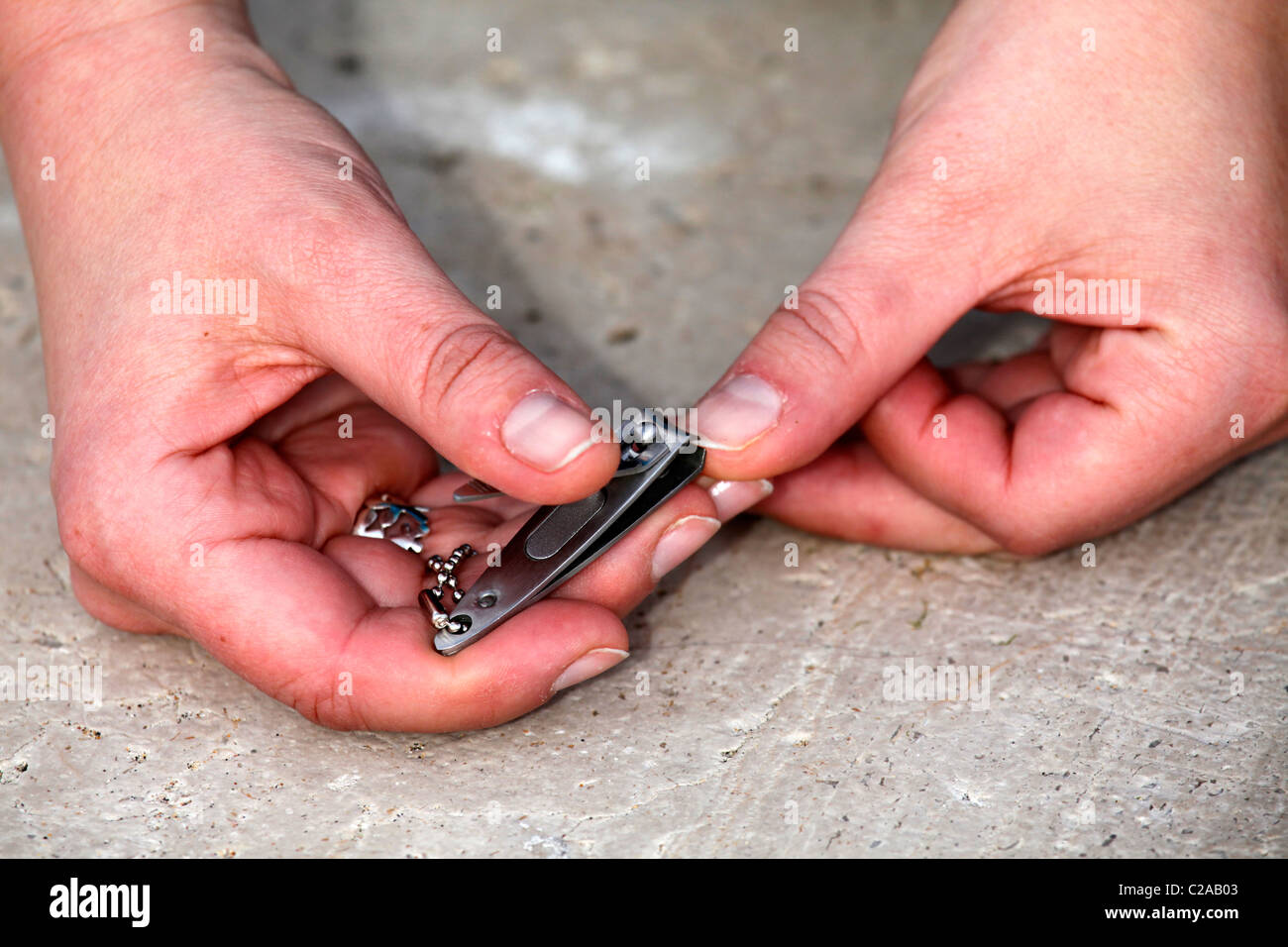 A Caucasian woman trims her nails with a nail clipper. Stock Photo