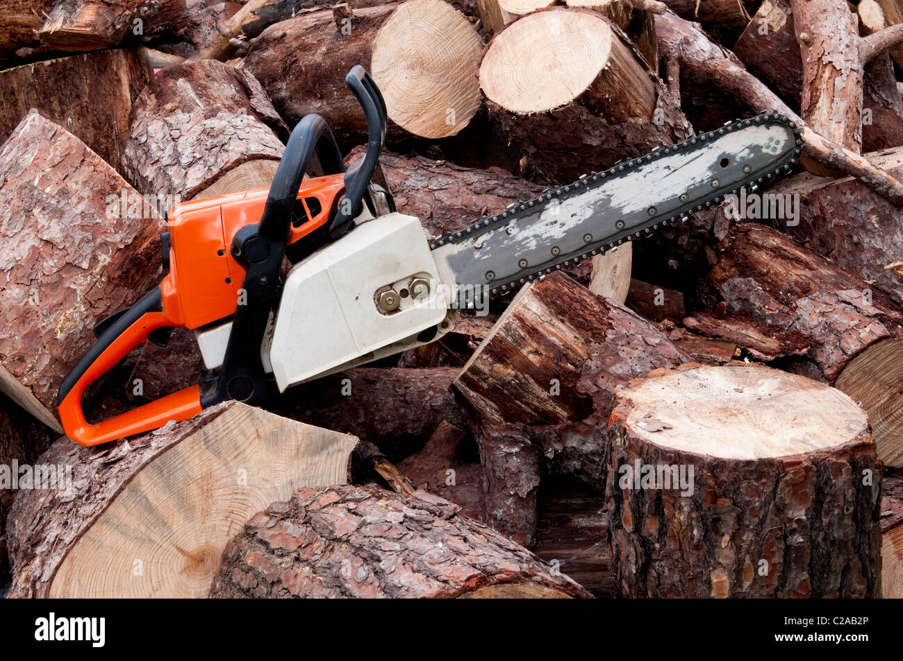 A chain saw sitting on a pile of logs Stock Photo