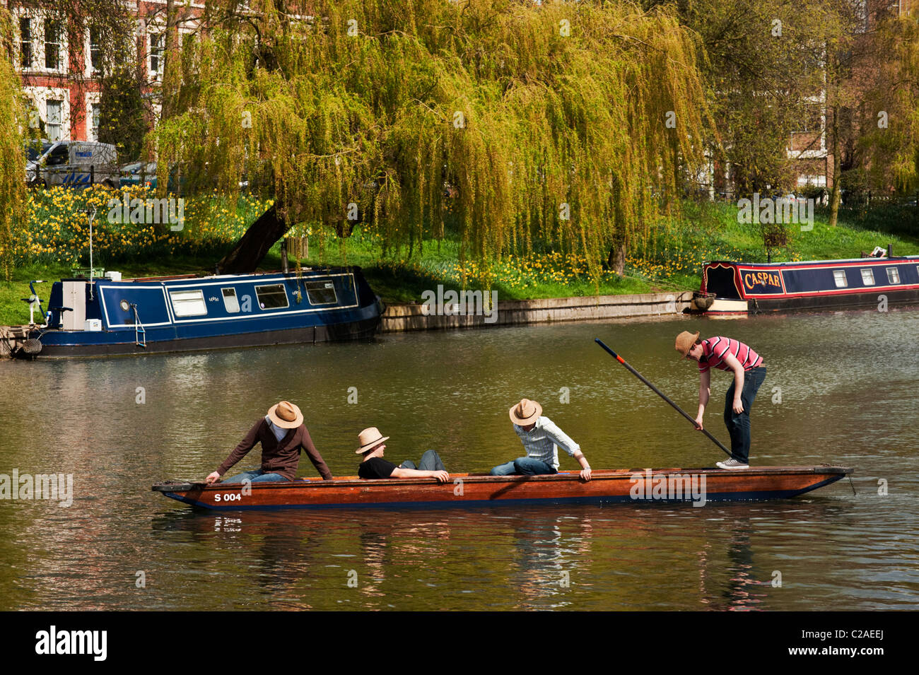 Four young men in straw hats punting on the River Cam on a fine spring day. Stock Photo