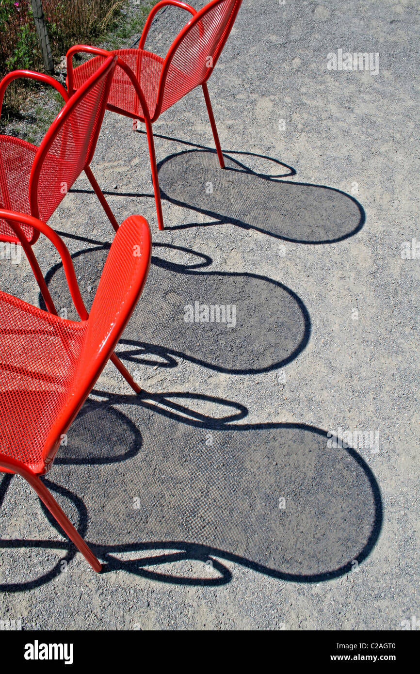 Red wire chairs shadows on concrete Stock Photo