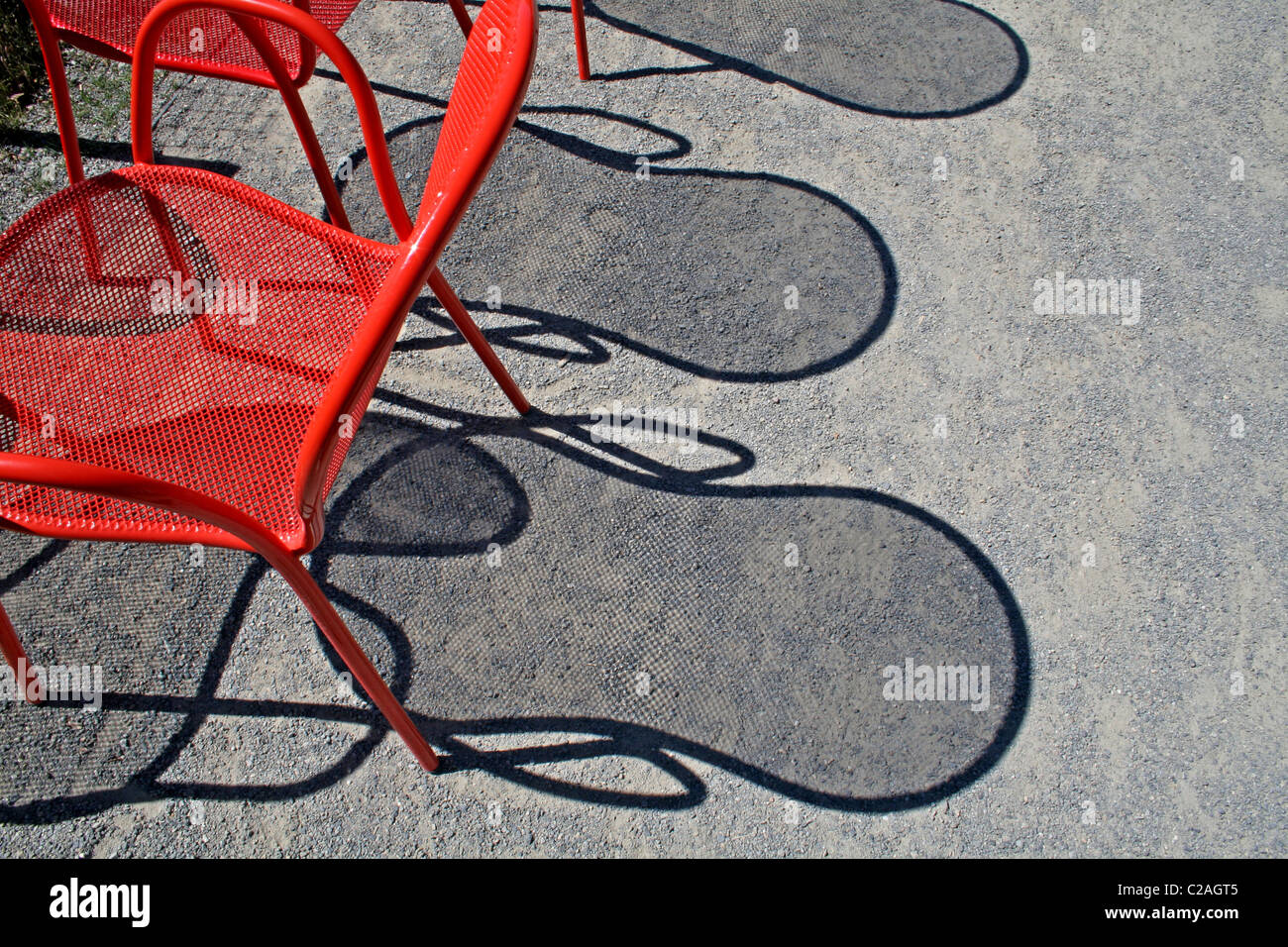 Red wire chairs shadows on concrete Stock Photo