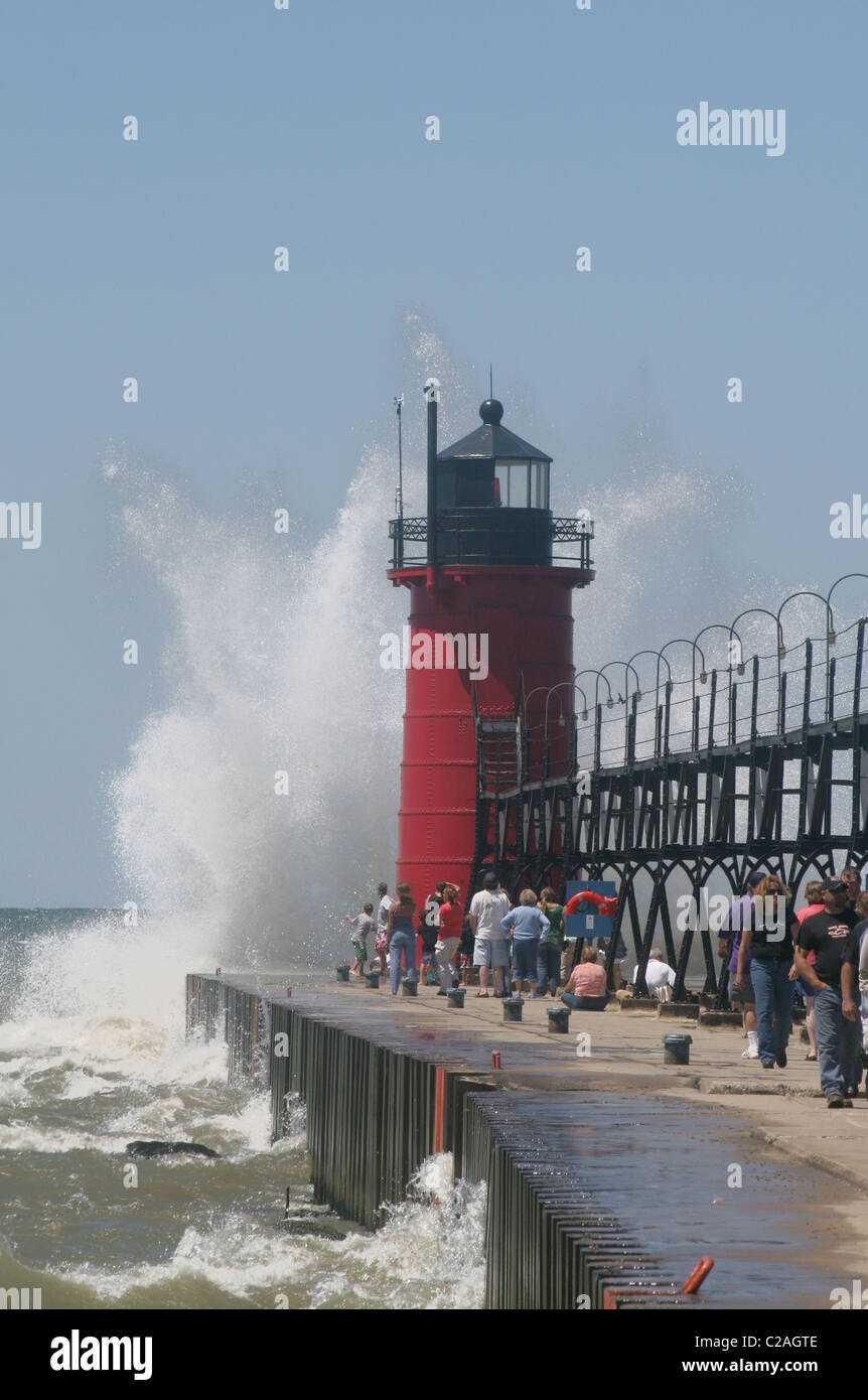 People on jetty watch large breaking waves in South Haven Michigan Stock Photo