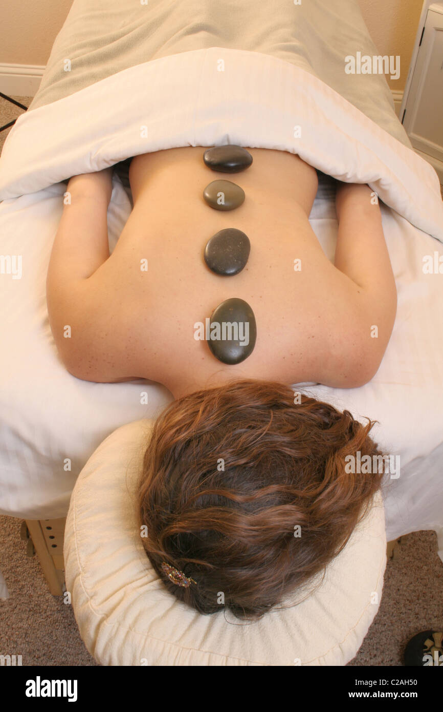 Released health spa woman heated stones on back Stock Photo