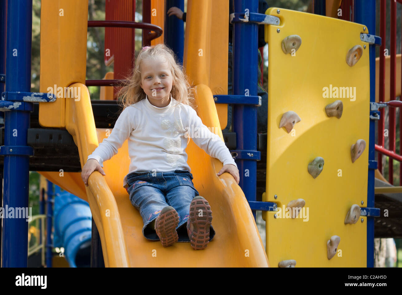 Smilling Girl On A Yellow Playground Slide Stock Photo - Alamy
