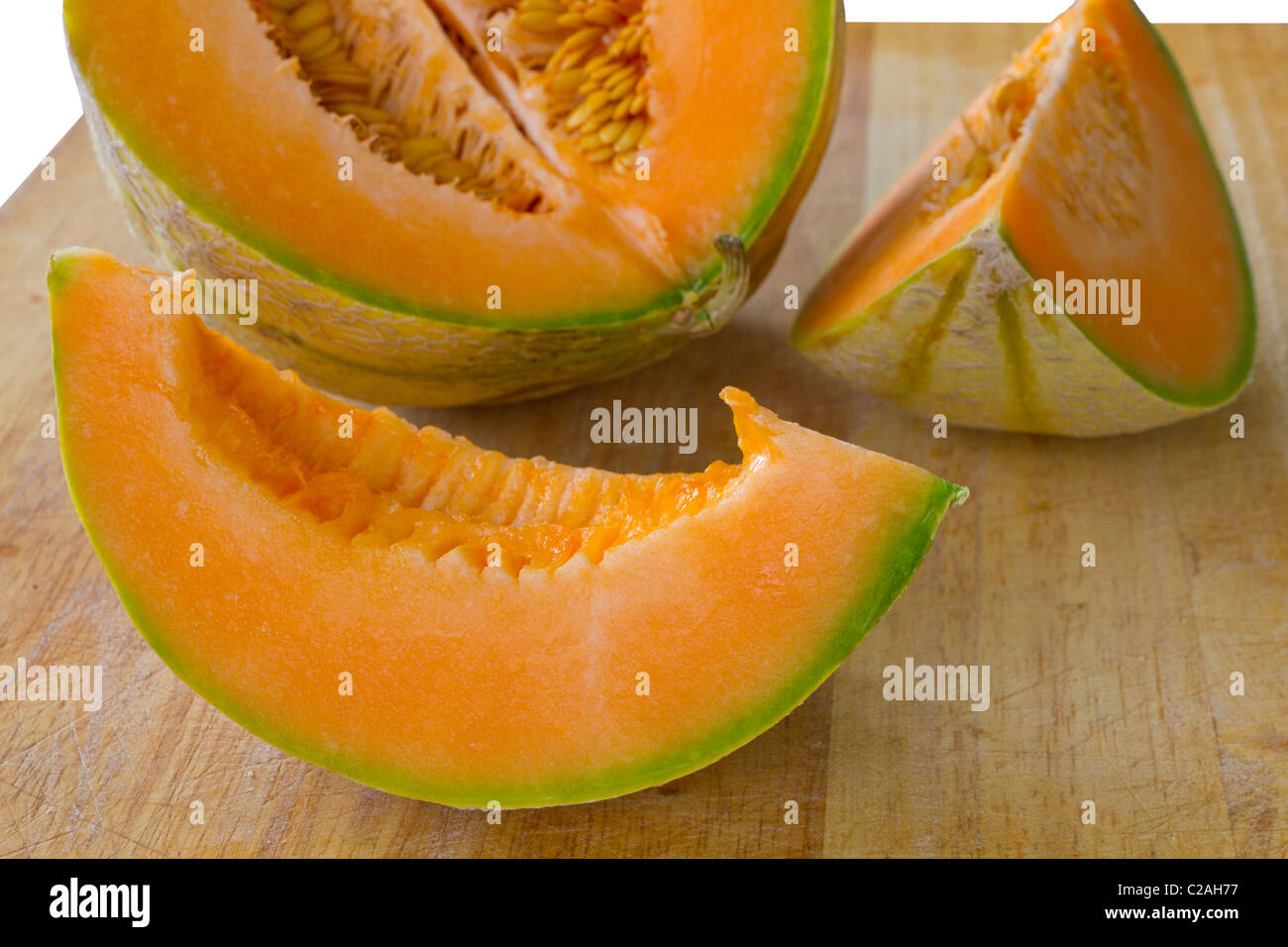sliced piece of fresh orange cantaloupe melon on wooden carving board Stock Photo