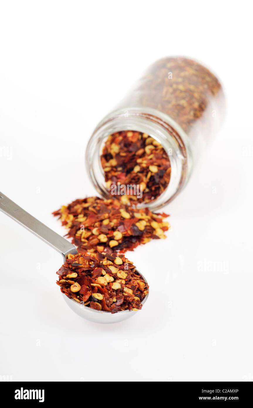 Bottle of hot crushed red pepper spice open and on it side with red pepper flake spilling out on white background, cutout Stock Photo
