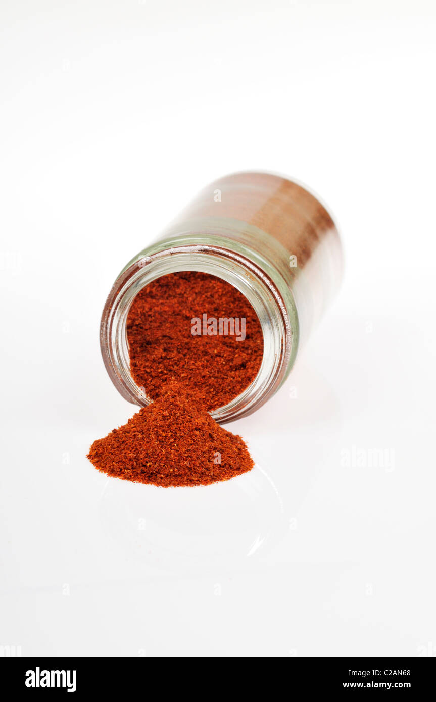 Bottle of cayenne pepper spice open and on it side with cayenne spilling out on white background, cutout. Stock Photo
