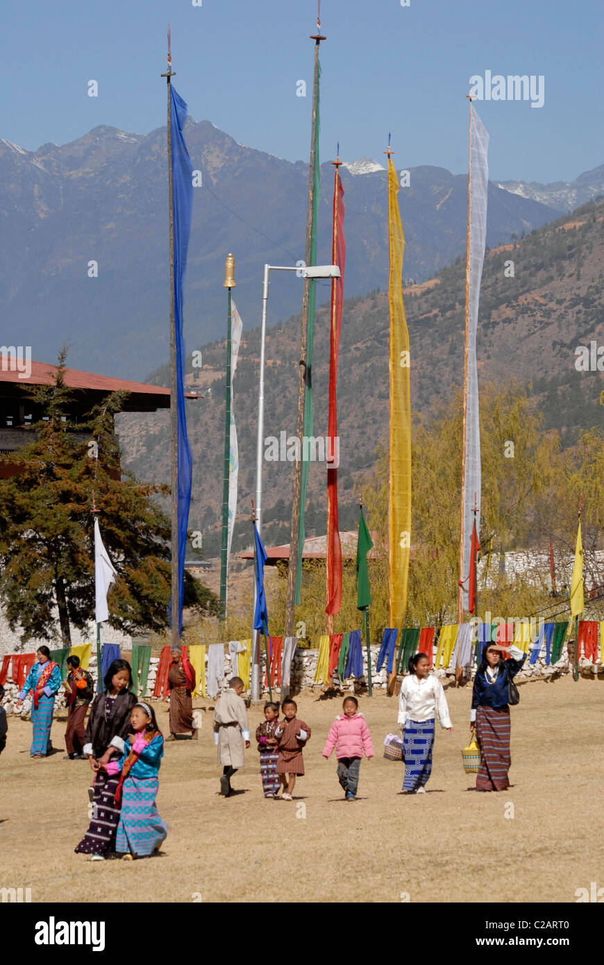 People arriving at the Paro Festival (Paro Tsechu), with prayer flags in front of the himalayan mountains, Paro, Bhutan Stock Photo