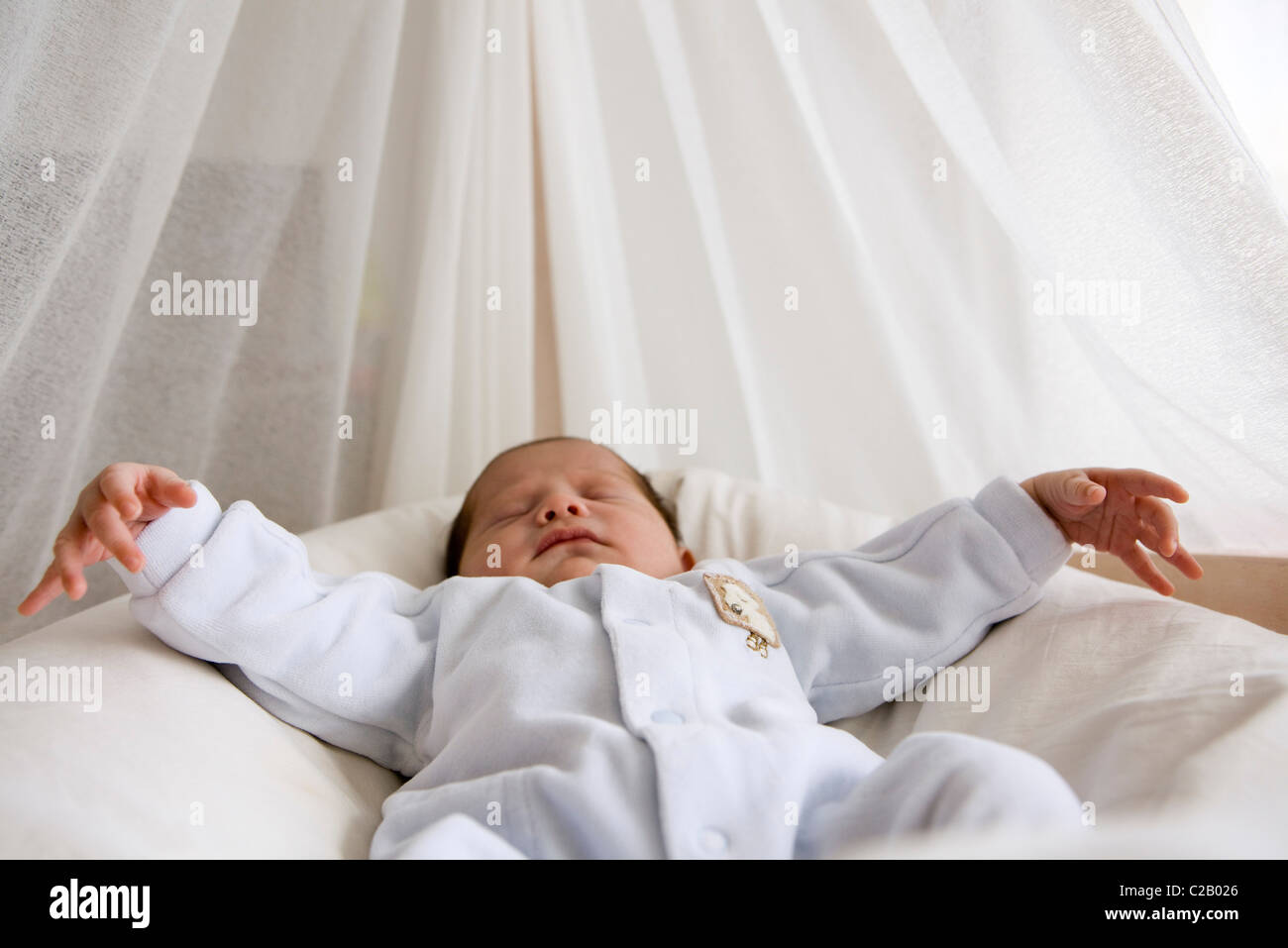 Baby sleeping in crib with arms out Stock Photo Alamy