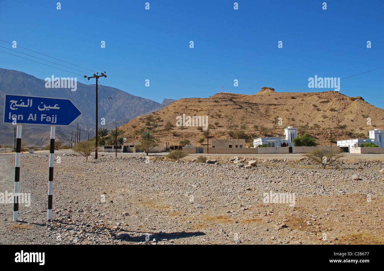 Oman, Ien al Fajj, arrow sign board on landscape with mountains in background Stock Photo