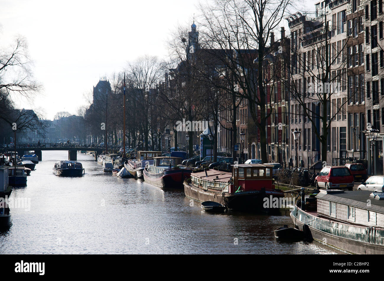 Canal in the Jordaan district in Amsterdam with houseboats and canal tour boat in the winter. Stock Photo
