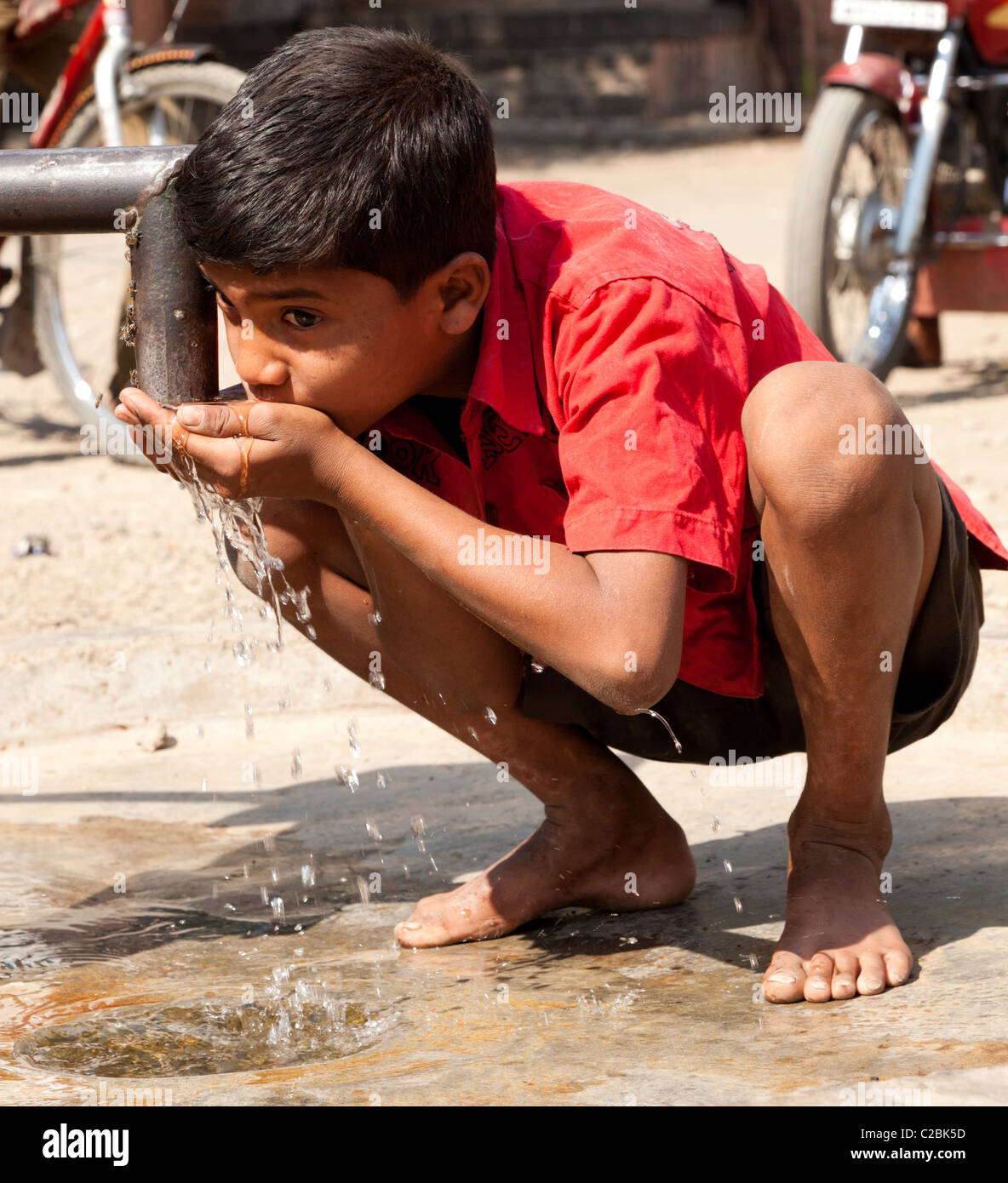 A boy drinks from a water pump in Valsang Village Maharashtra India Stock Photo