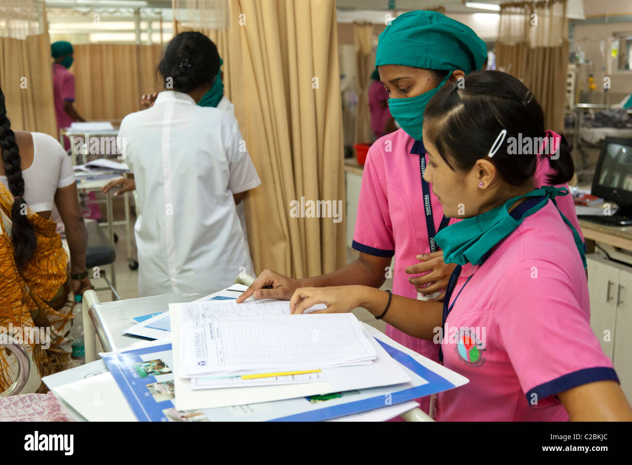 Nurses check a patients notes in an Intensive Care Unit (ICU) in Yashodhara Hospital Sholapur India Stock Photo