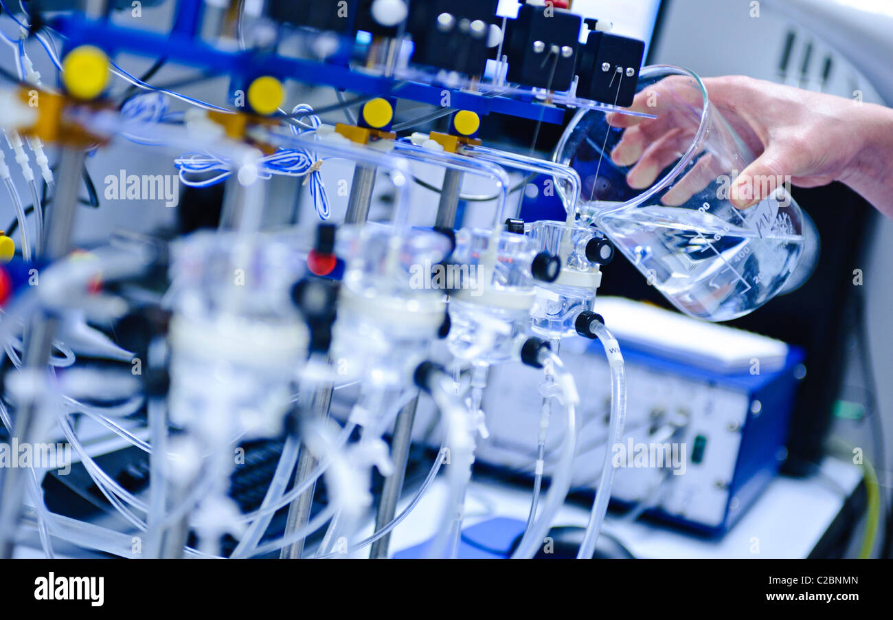 Glass beaker pouring clear solution into scientific apparatus in a