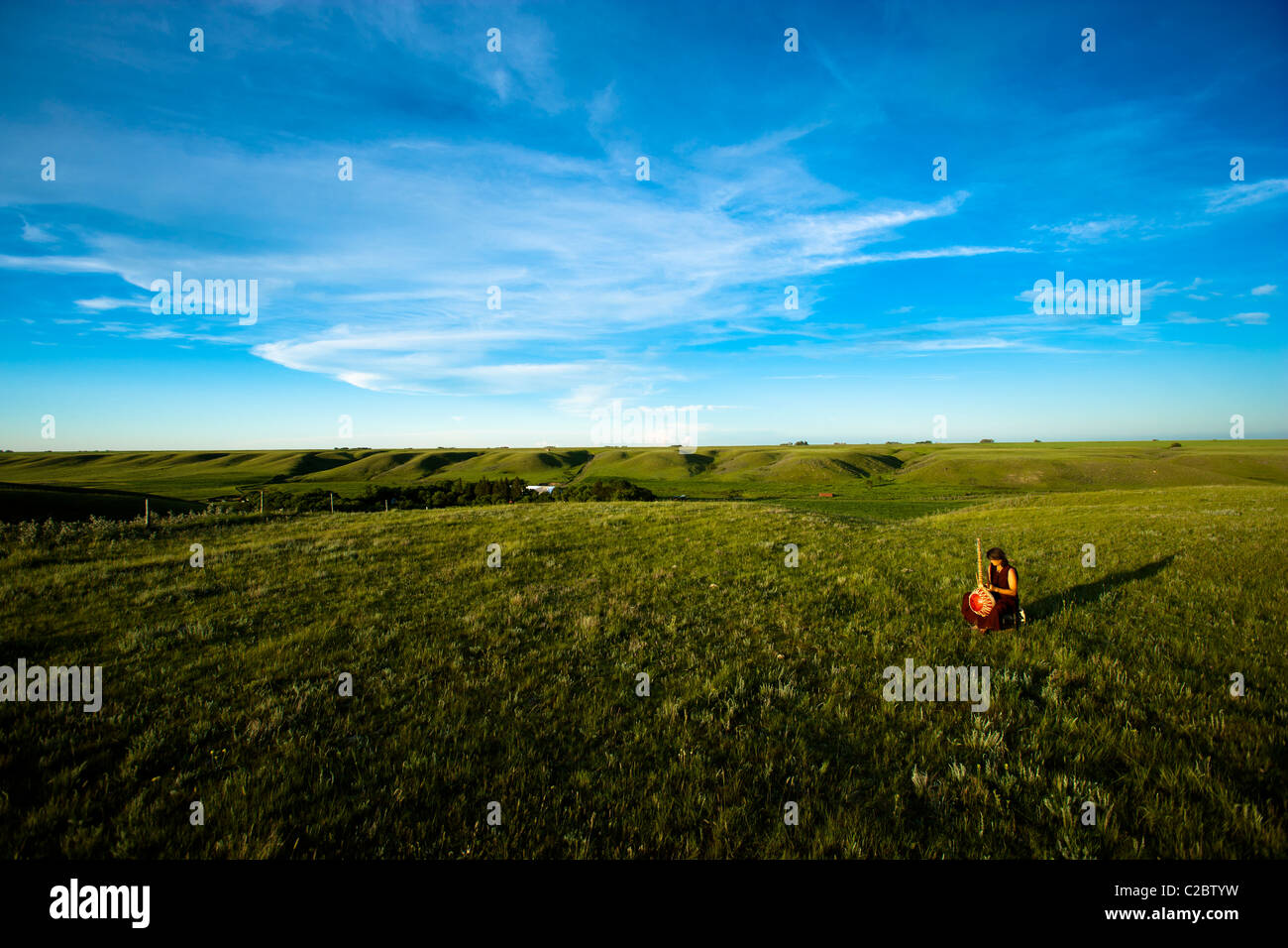Vast open space of the Canadian prairies with a lone female playing an instrument Stock Photo