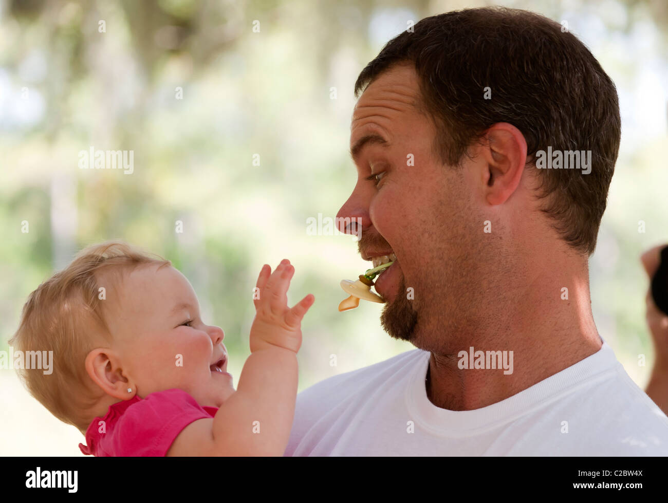 Eight month old baby trying to take dummy from father Stock Photo Alamy