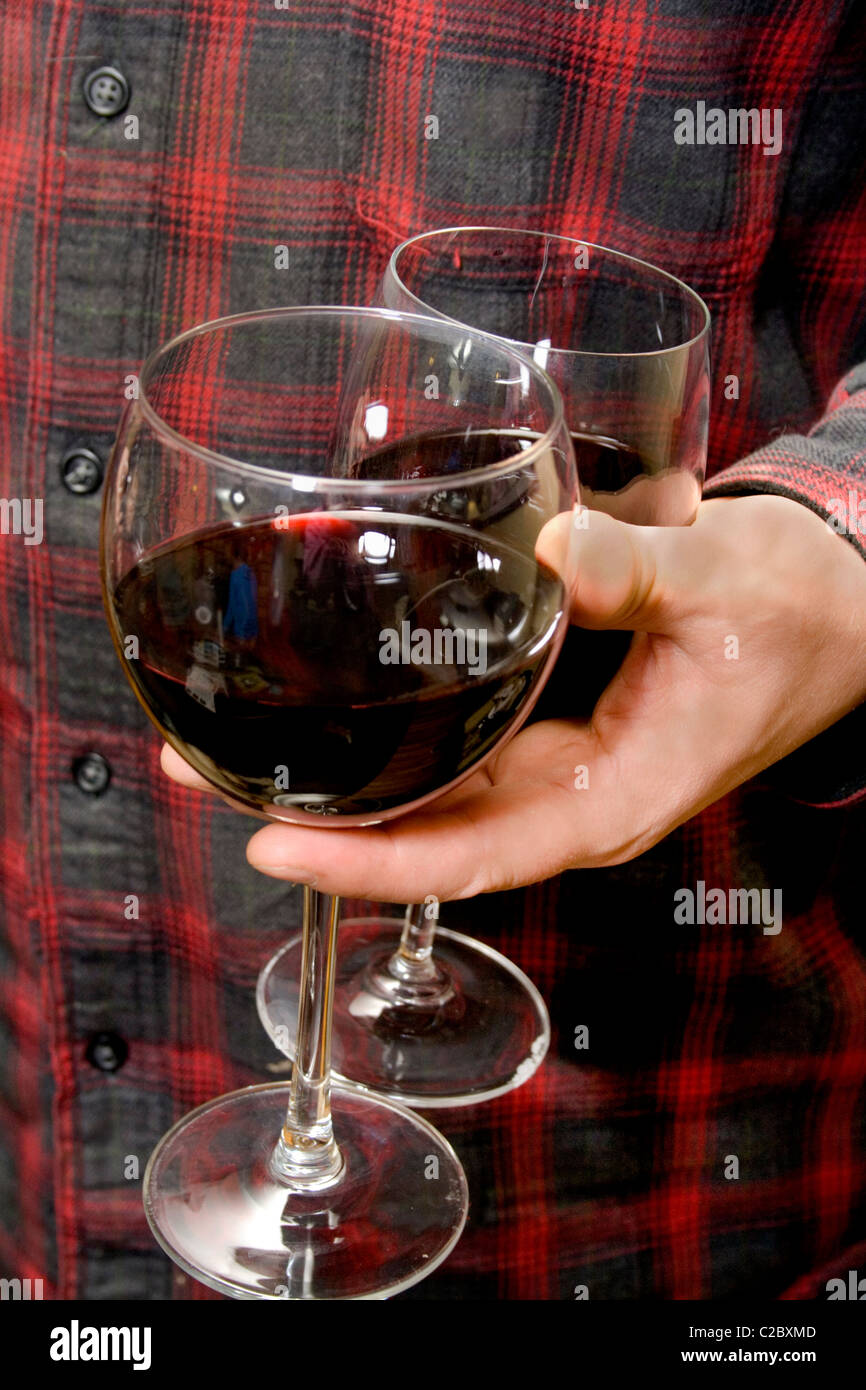 Host carrying two stemmed glasses containing red wine. St Paul Minnesota MN USA Stock Photo